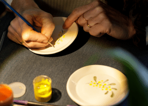 des mains qui peignent les dessins de mimosa sur la céramique